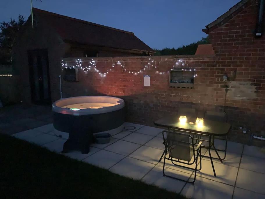 a bath tub sitting on a patio with a table at The Lodge - Dog Friendly Farm Cottage in Norwich