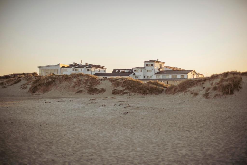 um grupo de casas no topo de uma praia arenosa em Sola Strand Hotel em Sola