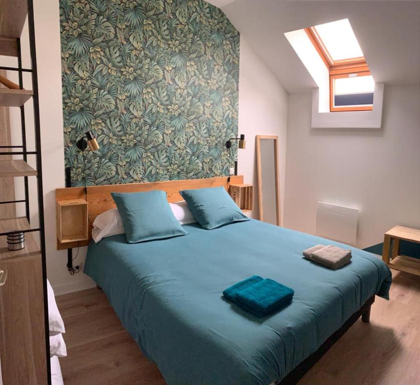 a bedroom with a large bed with blue pillows at latypique family in Bourges