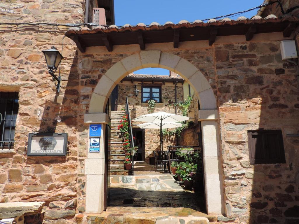 une arche dans un bâtiment en pierre avec un parasol dans l'établissement El Rincón Maragato, à Castrillo de los Polvazares