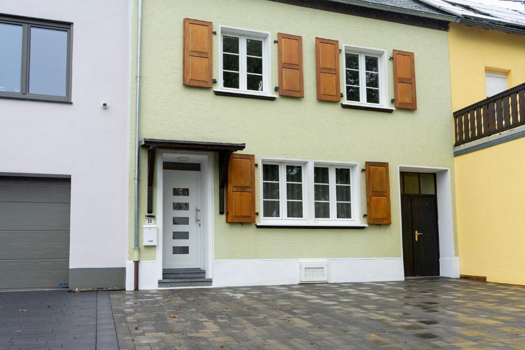 una casa gialla e bianca con finestre e una porta di Ferienhaus Reuter a Schweich