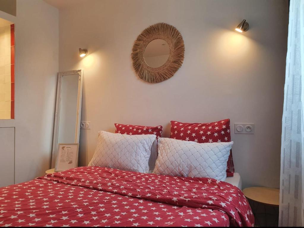 - un lit avec des oreillers rouges et blancs et un miroir dans l'établissement Appartement moderne proche de CDG & Parc d'Expo,stade de France, à Aulnay-sous-Bois