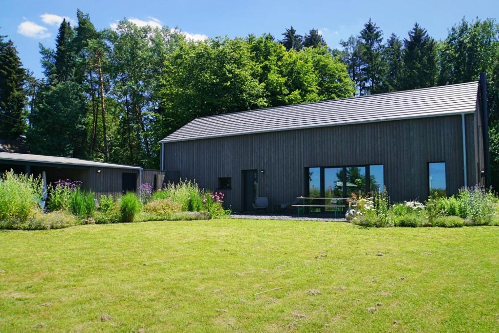 un bâtiment noir avec une cour devant lui dans l'établissement Wäller Haus - Modern villa with fireplace & large natural garden, à Breitscheid