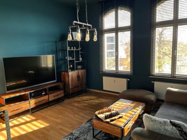 ein Wohnzimmer mit einem großen TV und einem Tisch in der Unterkunft Ferienwohnung "Charlotte" nahe der Elbe mit kostenlosem Parkplatz vor der Tür in Magdeburg