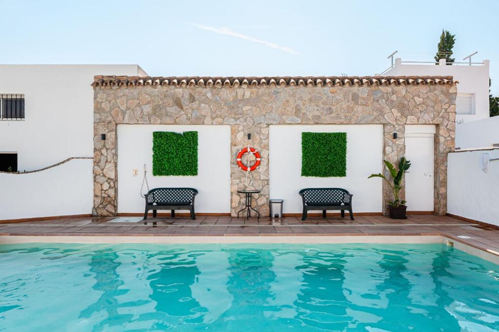 una piscina con due sedie e un tavolo accanto a un muro di Villa Fuentes Sólo Familias a Conil de la Frontera