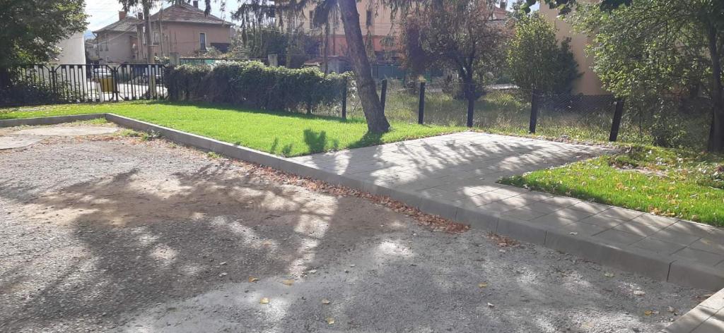 a walkway in a driveway with a tree in a yard at Hostel Iliana Общежитие Илияна in Elin Pelin