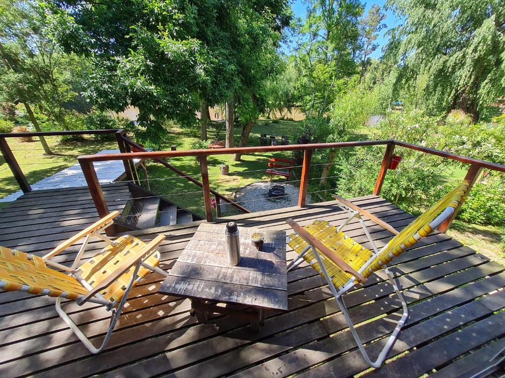 una terraza de madera con 2 sillas y una mesa de madera en Cabaña Sol de Medianoche Delta Tigre en Tigre