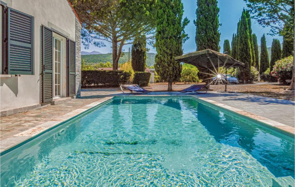 サン・フロランにあるStunning Home In St Florent With 5 Bedrooms, Wifi And Outdoor Swimming Poolの傘付きの家屋裏庭のスイミングプール