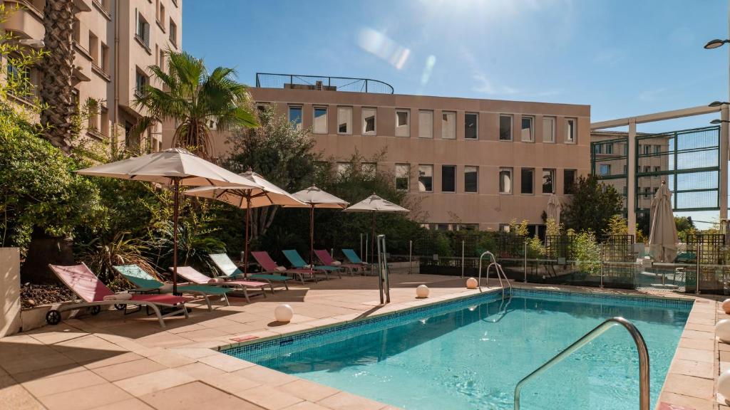 a swimming pool with chairs and umbrellas next to a building at Holiday Inn Toulon City Centre, an IHG Hotel in Toulon