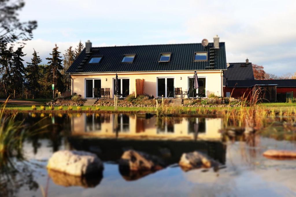 een huis met een reflectie in een vijver bij Naturferienhof Märkisch Luch 