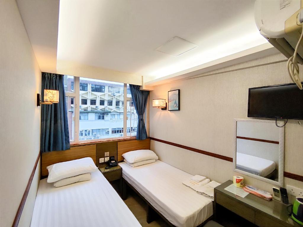 a room with two beds and a tv and a window at Celltronik Hostel 先創旅店 in Hong Kong