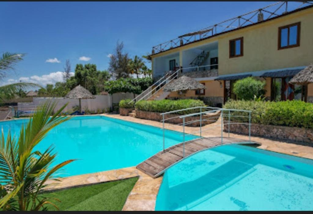 a large blue swimming pool in front of a house at Jua Apartments in Kiwengwa