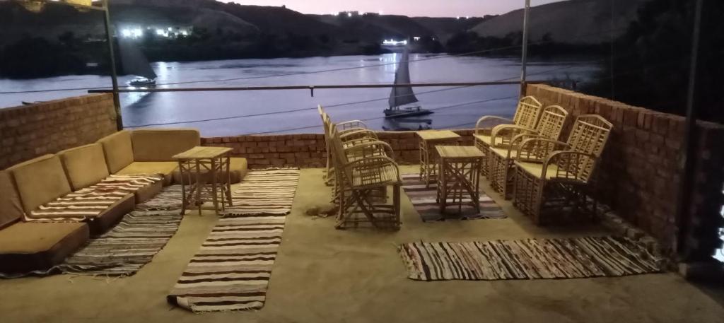 a patio with chairs and tables and a view of the water at Golden nubian guesthouse in Aswan