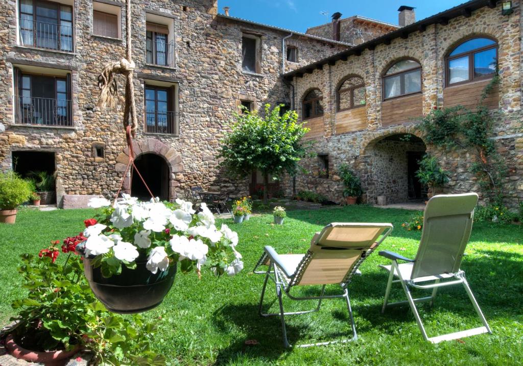 un jardín con 2 sillas, una mesa y flores en La Era de Navarri - Bonansa, en Bonansa