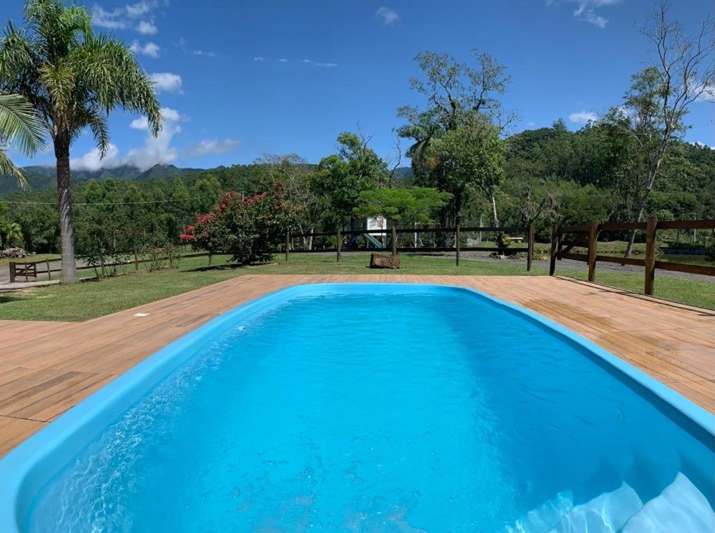 勞魯米萊的住宿－Pousada Costão da Serra，一个带木制甲板的大型蓝色游泳池