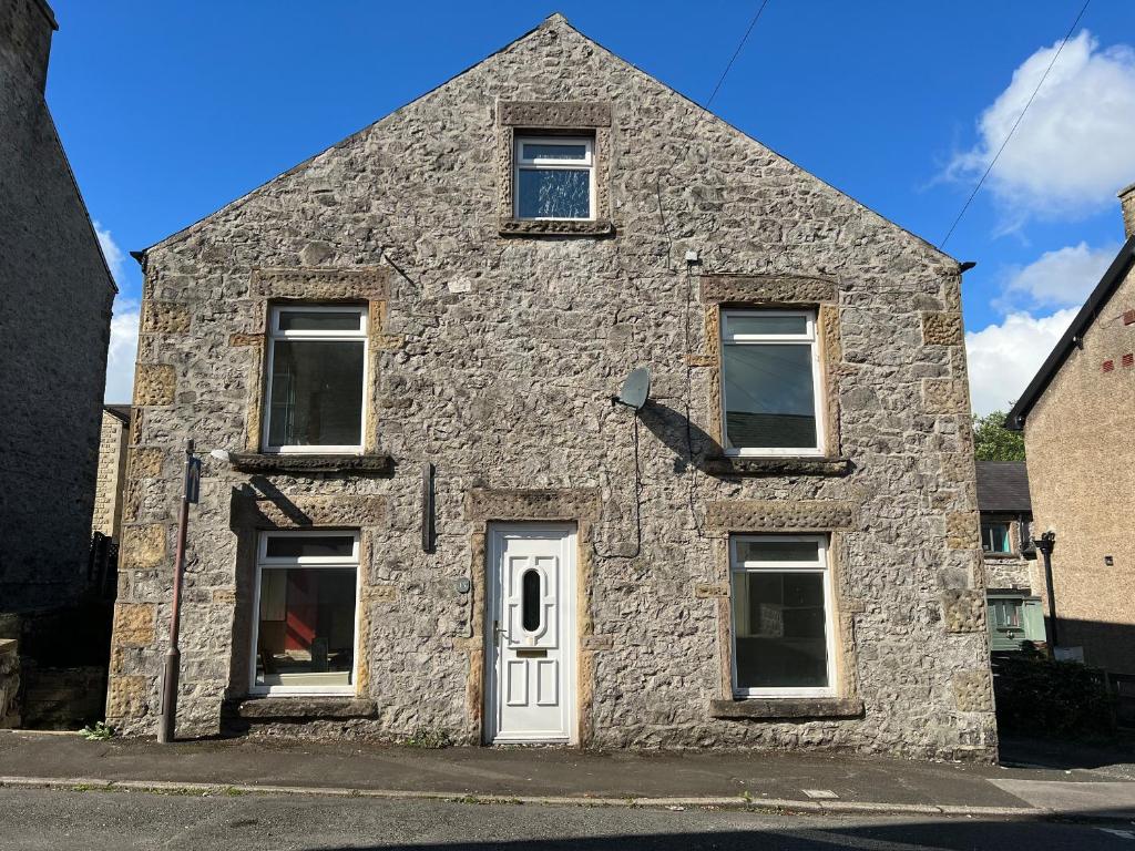 an old stone building with a white door and windows at Alma Cottage in Buxton
