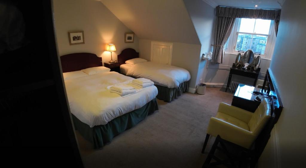 una habitación de hotel con dos camas y una silla en A-Haven Townhouse Hotel, en Edimburgo