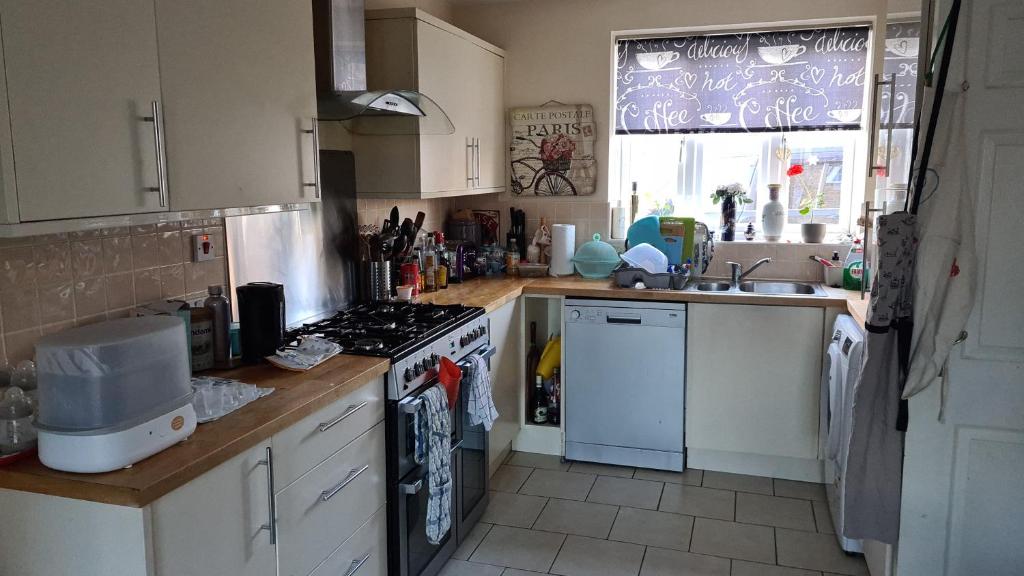 a kitchen with white cabinets and a stove top oven at Brightly lit double room is available in a home in Corby