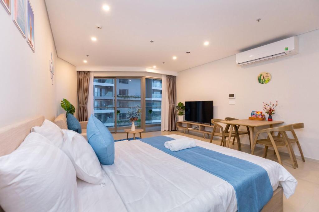 a bedroom with a large white bed and a table at Phúc Khang Luxury Apartment - The Sóng Vũng Tàu in Vung Tau