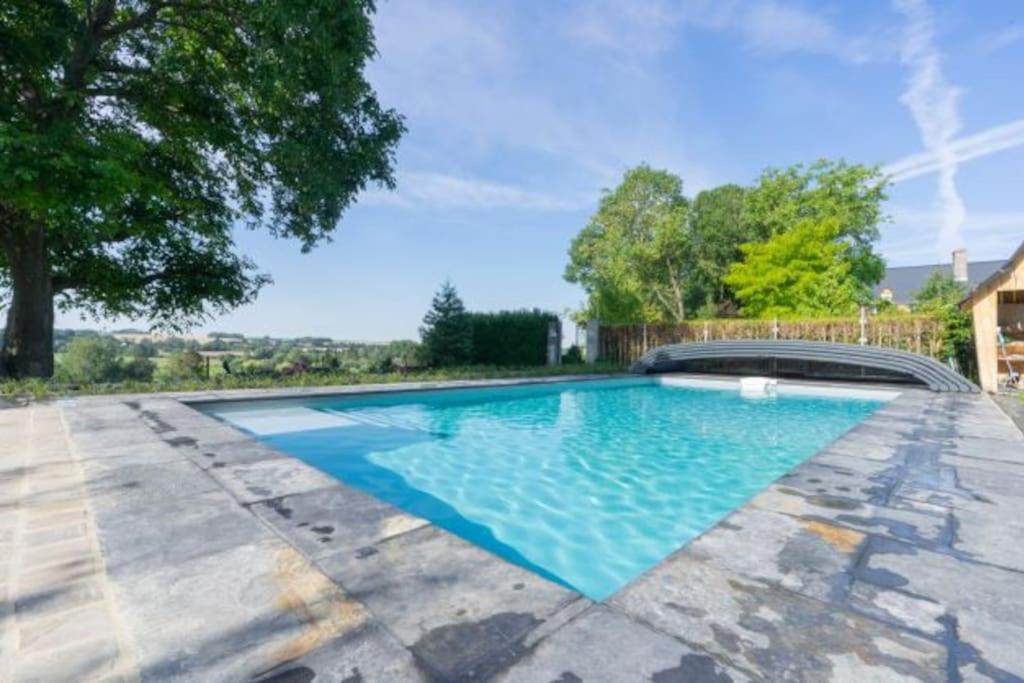 een zwembad met blauw water in een tuin bij Vakantiewoning Le Chêne 