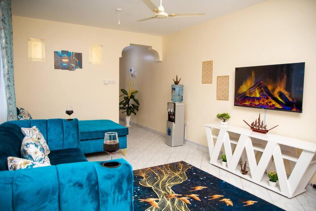 een woonkamer met een blauwe bank en een tv bij Royal Haven A3 Spacious 1Br Apartment 10min drive to beach hosts upto 4 guests WiFi - Netflix, 10min drive to beach in Mombasa