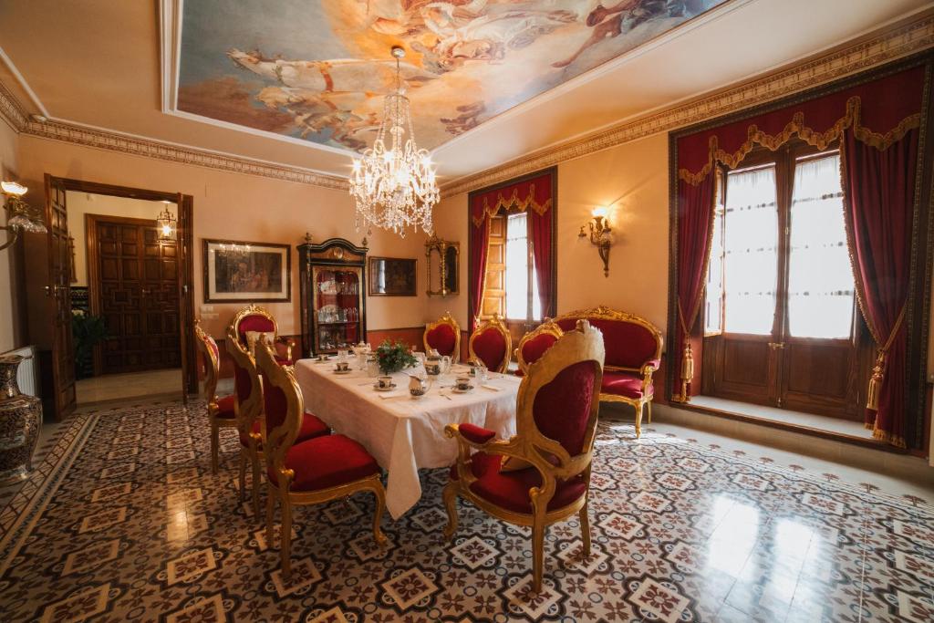 een eetkamer met een tafel en stoelen en een kroonluchter bij Andalusian Palace in Priego de Córdoba