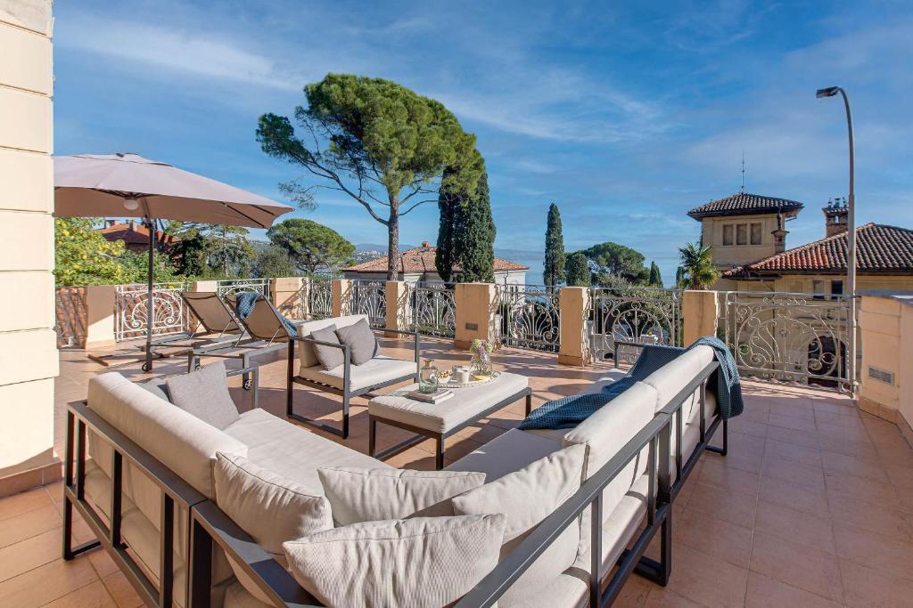 a patio with a bunch of chairs and an umbrella at Luxury Seaview Apartment in Opatija