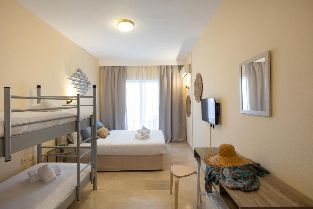 アギオス・イオアニス・ペリステリオンにあるAurora Beach Hotelの二段ベッド2台とテーブルが備わる客室です。