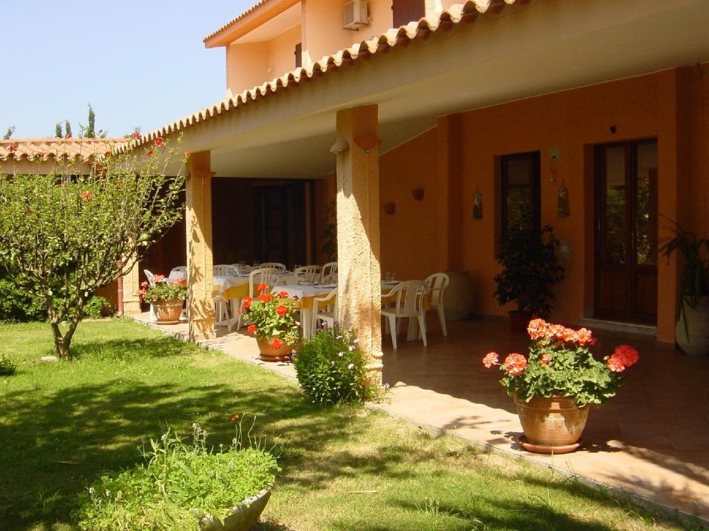a house with a patio with a table and chairs at Hotel Su Giudeu in Chia