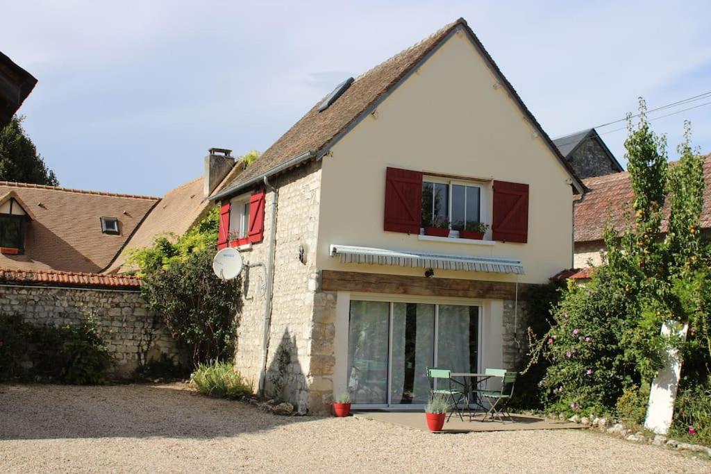 a house with red windows and a table in front of it at Maison La Plage cadre verdoyant et calme in Port-Mort