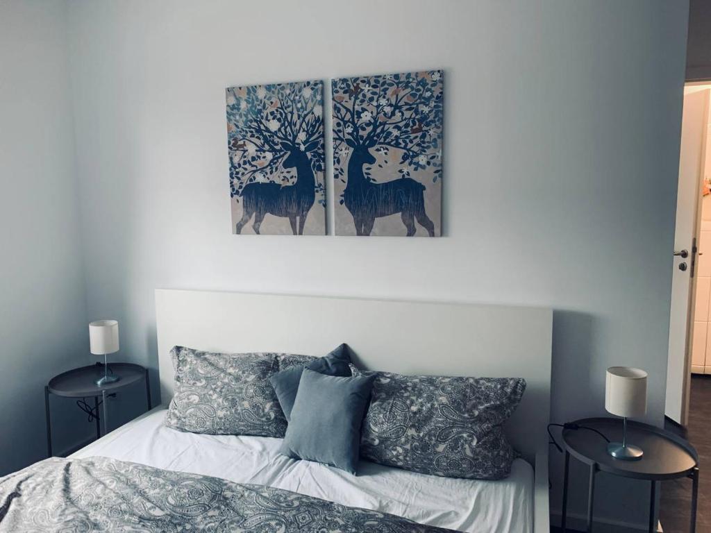ein Schlafzimmer mit einem Bett mit zwei Gemälden an der Wand in der Unterkunft Apartment mit Penthouse Charakter in Dresden in Dresden