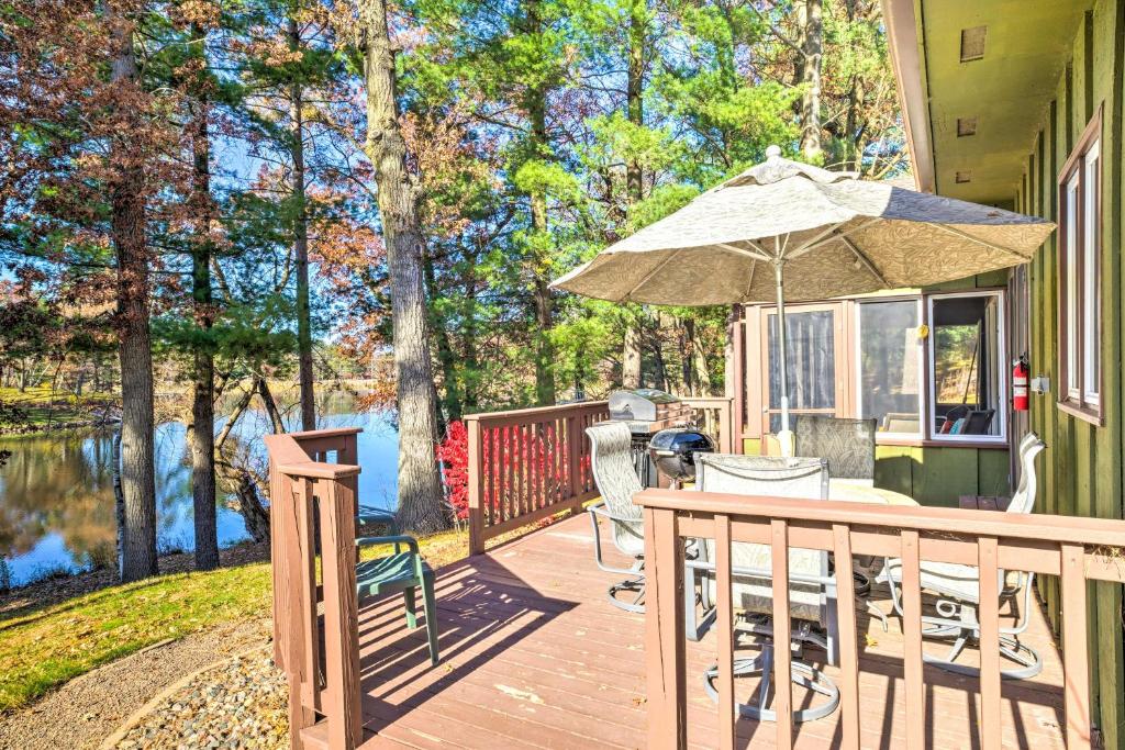 een houten terras met een tafel en een parasol bij Beautiful Home with Hot Tub on Lake Wissota in Chippewa Falls
