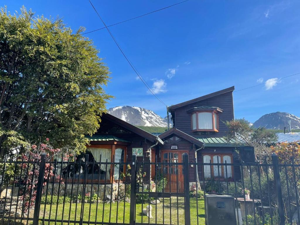 una casa con una valla y montañas en el fondo en Ulen en Ushuaia