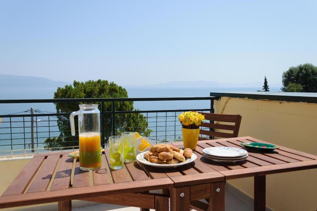 einem Holztisch mit einem Teller mit Lebensmitteln und Orangensaft in der Unterkunft Beautiful seaside studio with amazing view in Athen