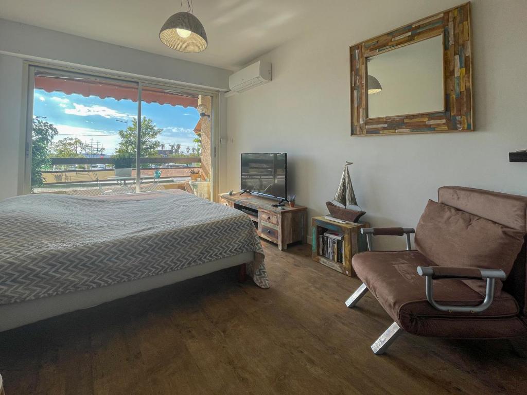 una camera con letto, sedia e specchio di Les balcons de Bandol Centre ville avec vue mer et face à la plage a Bandol