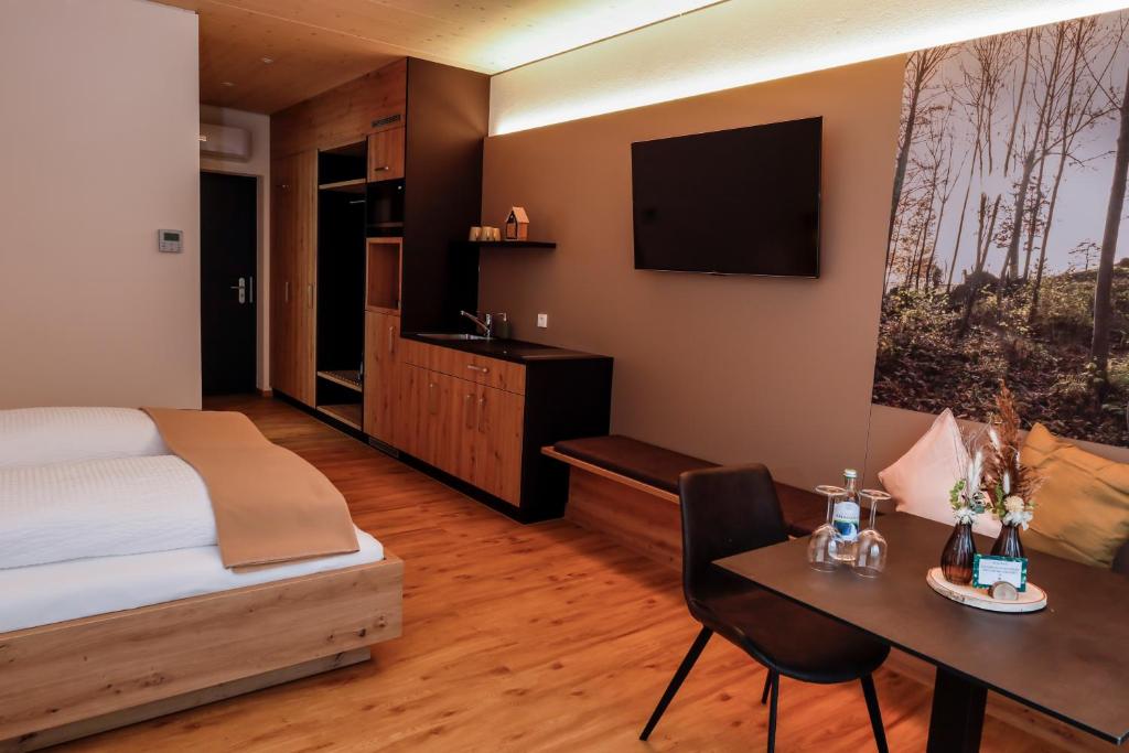 een slaapkamer met een bed, een bureau en een televisie bij DAS GEORG Gästehaus in Epfendorf 