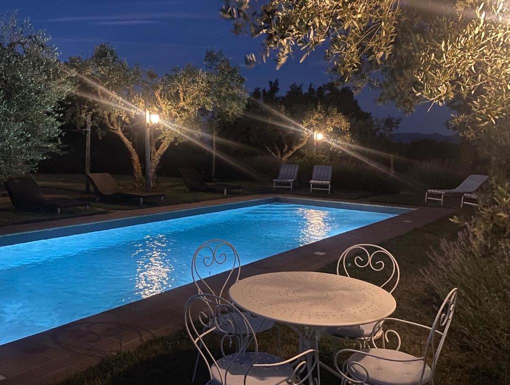 een tafel en stoelen naast een zwembad in de nacht bij B&B La Cervaiola in Porano