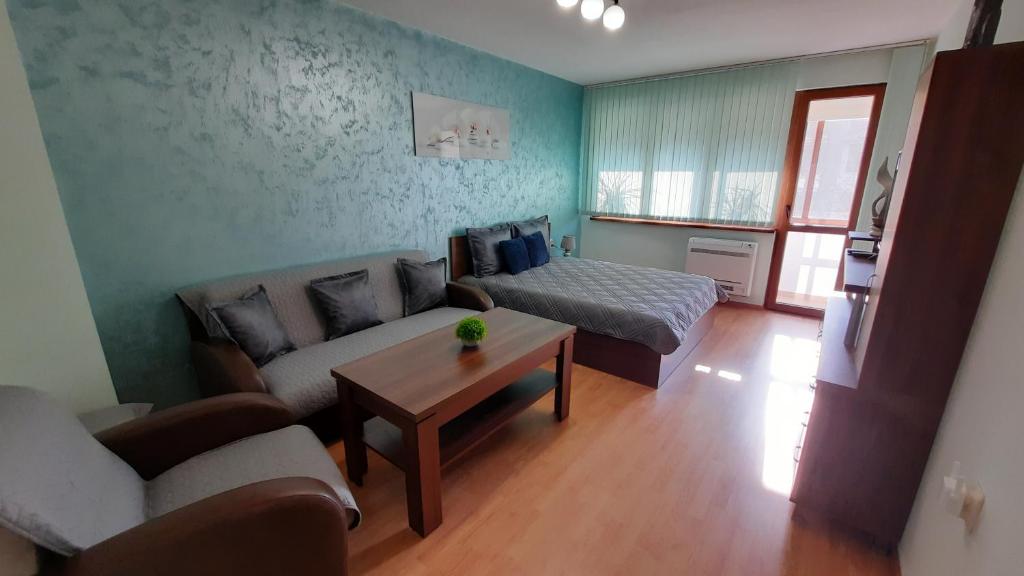 - un salon avec un canapé et un lit dans l'établissement Апартамент Миг, à Haskovo