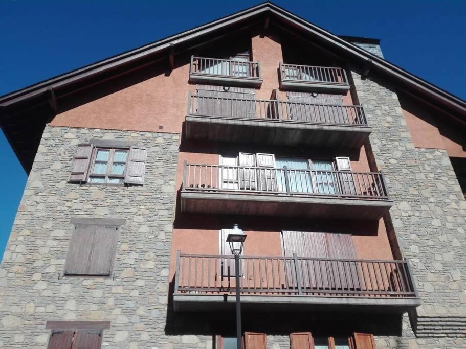 un edificio alto de ladrillo con balcones y luz de la calle en Apartamento Duplex Esterri ideal para familias en Esterri d'Àneu