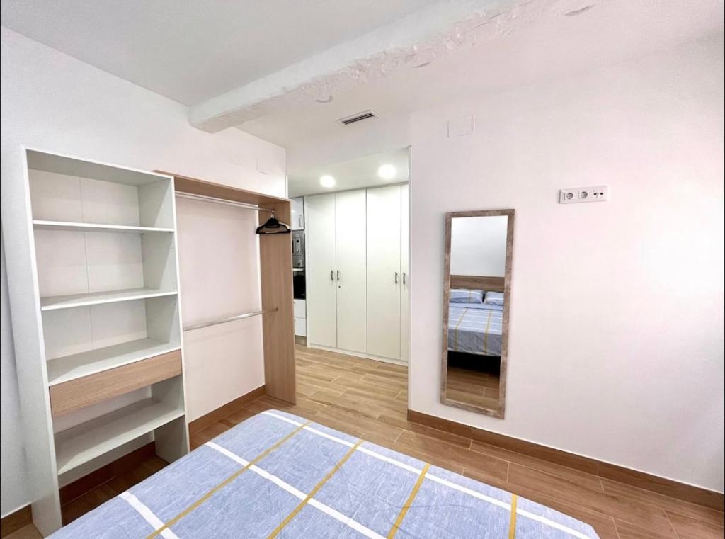 Habitación con paredes blancas, espejo y cama. en Maximilian Dreams, en Madrid