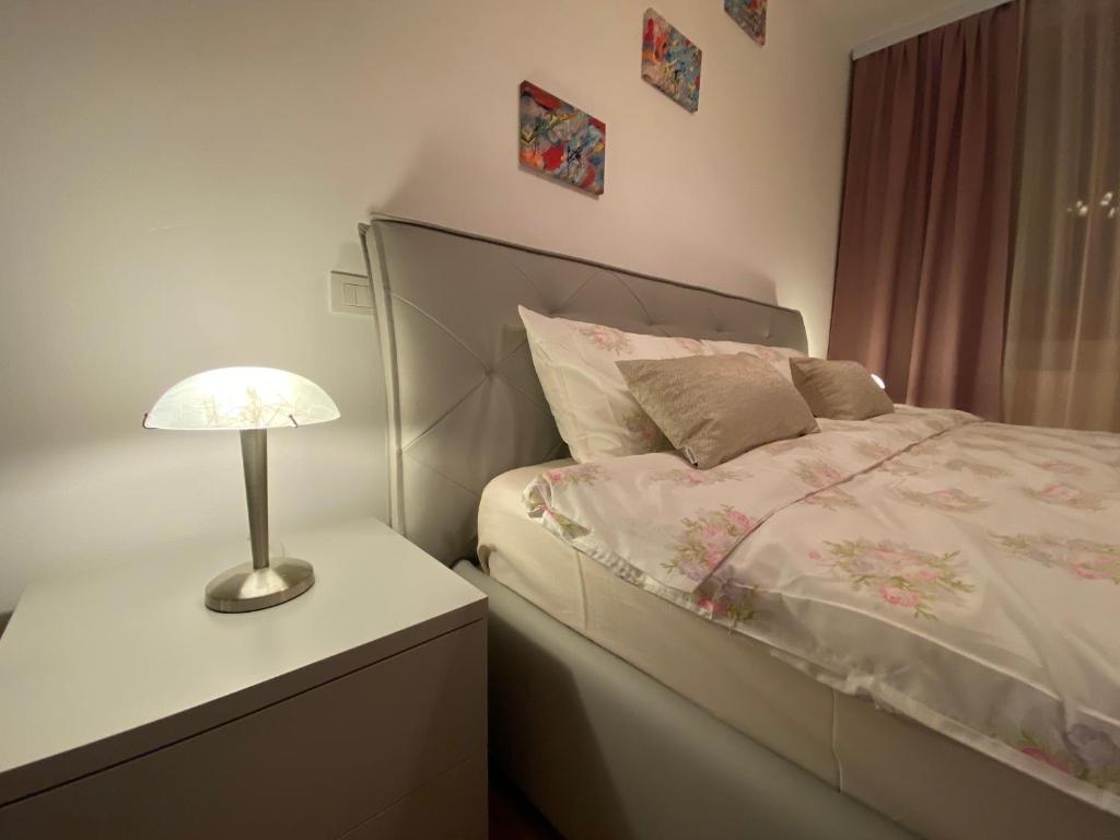 een slaapkamer met een bed en een lamp op een nachtkastje bij Central Apartment in Timişoara