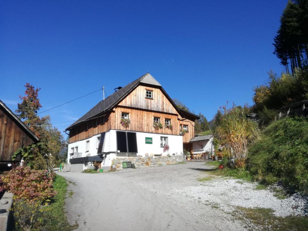 une grande maison en bois sur un chemin de terre dans l'établissement Landhaus Gschmeidler, à Selzthal