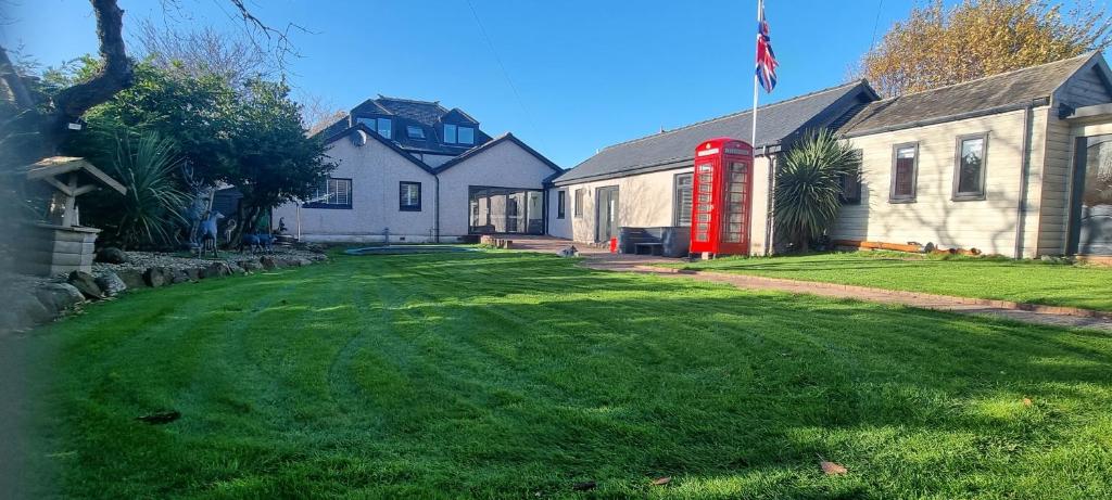 a yard with a red phone booth in front of a house at Laighdykes Guest Cottage in Saltcoats