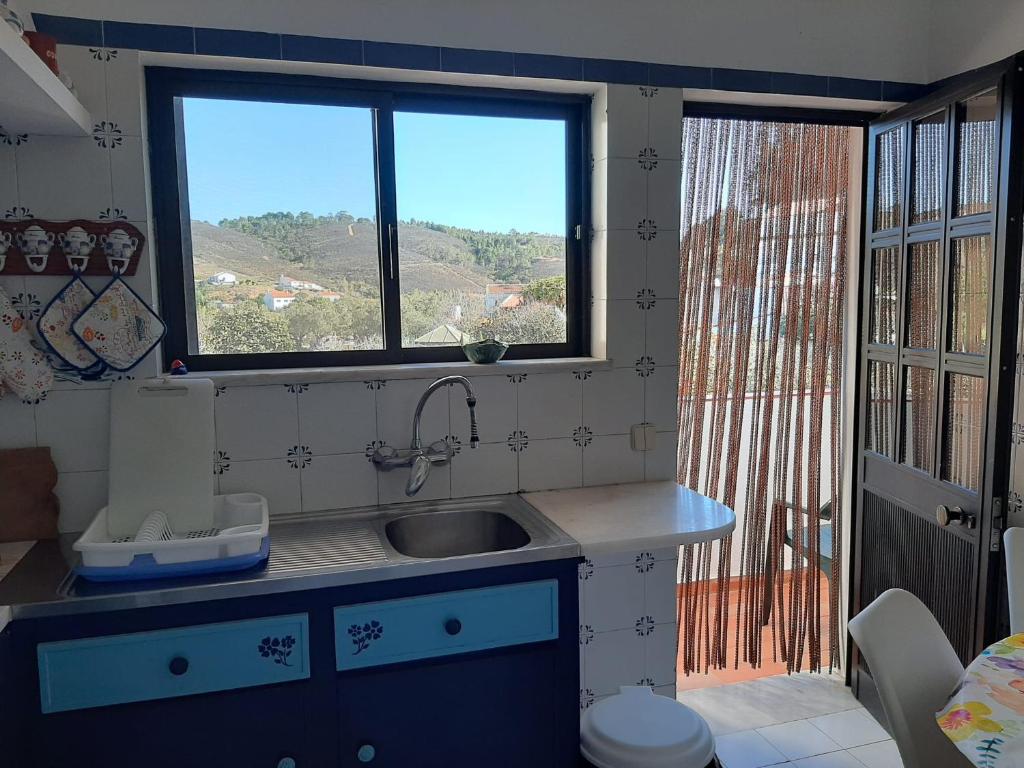 eine kleine Küche mit einem Waschbecken und einem Fenster in der Unterkunft Casa dos Pais in Odeceixe