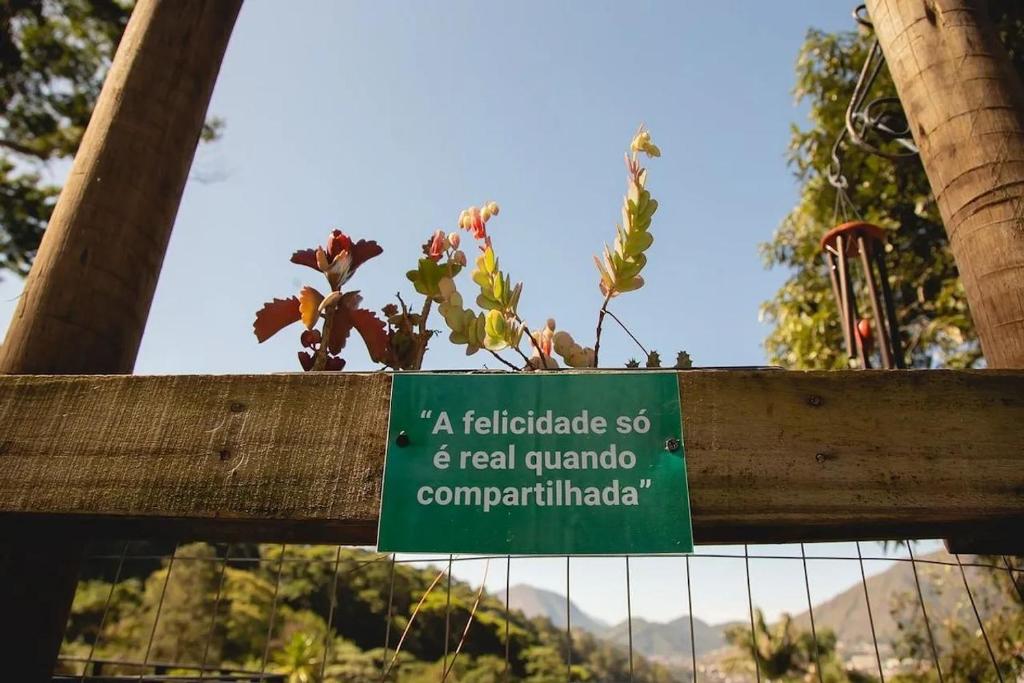 un panneau sur une clôture avec une plante en pot dans l'établissement Motorhomes na Serra, à Teresópolis