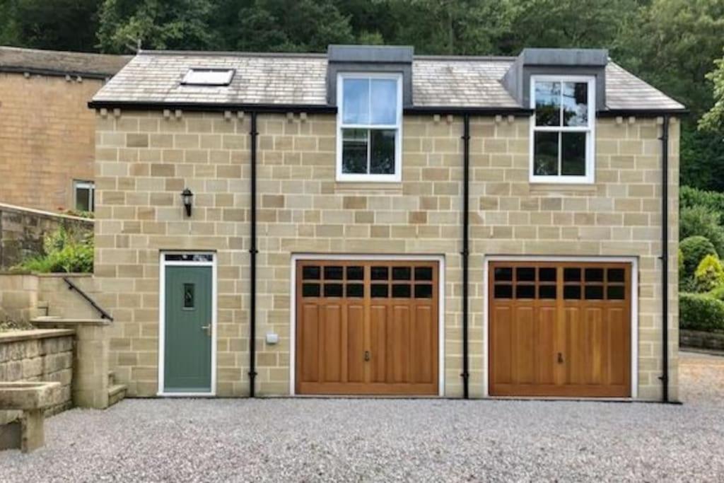 uma casa de tijolos com duas portas de garagem numa entrada em The Coach House - *New Build in Traditional Style* em Todmorden