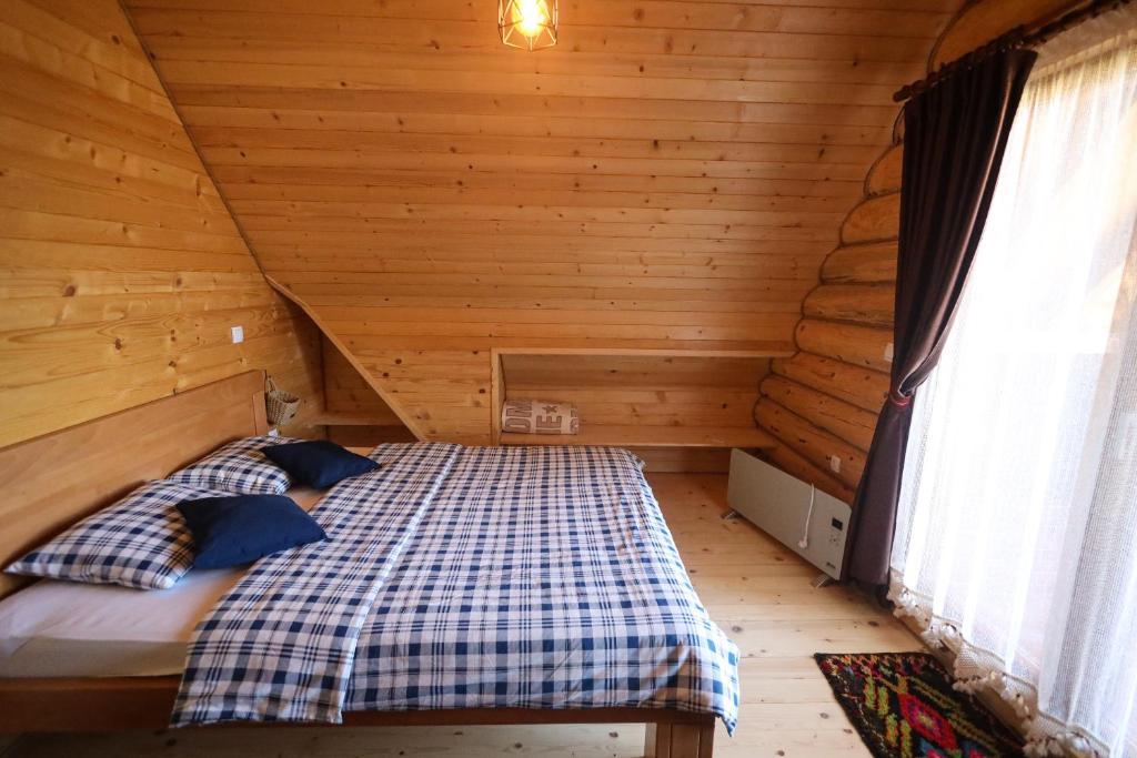 a bedroom with a bed in a wooden cabin at Brvnara Pahuljica Zlatar in Nova Varoš