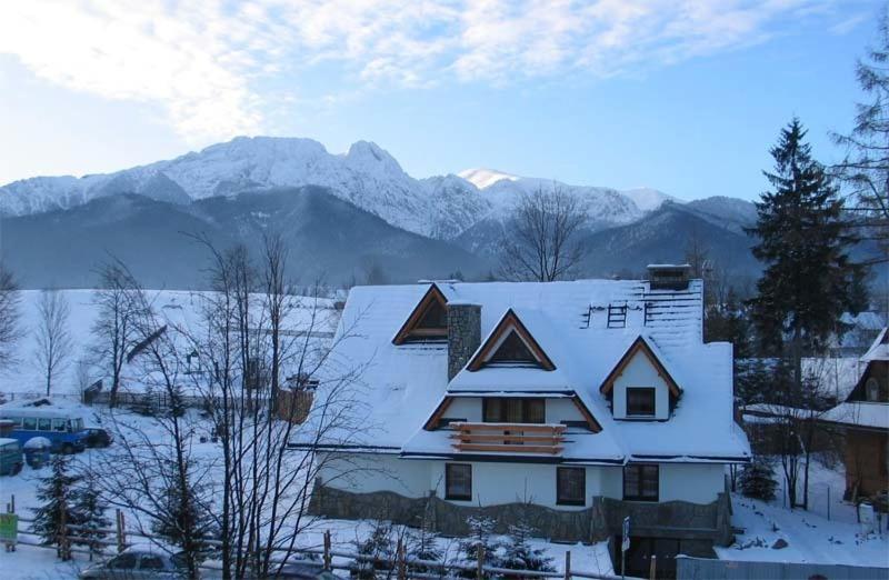 a house covered in snow with mountains in the background at Willa Jafer - Zakopane Centrum in Zakopane