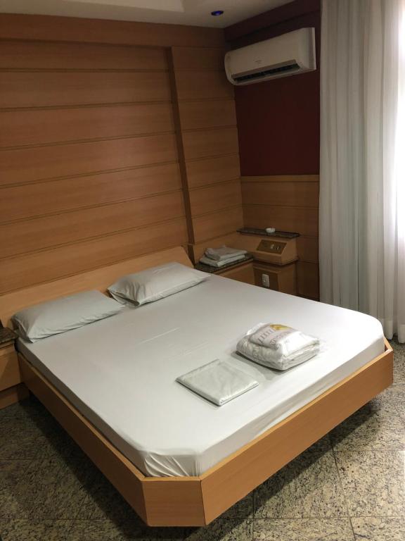 um quarto com uma cama com lençóis brancos e uma janela em Hotel Serrano no Rio de Janeiro