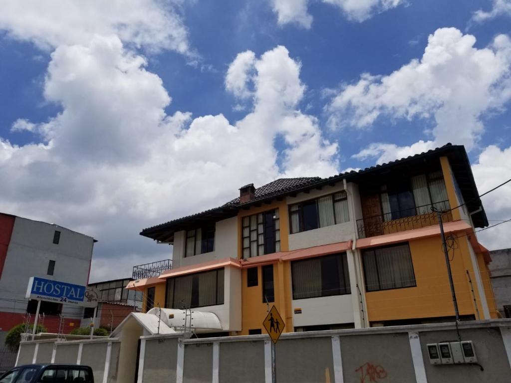 un edificio blanco y amarillo detrás de una valla en HOSTAL EL CONFORT QUITO NORTE, en Quito